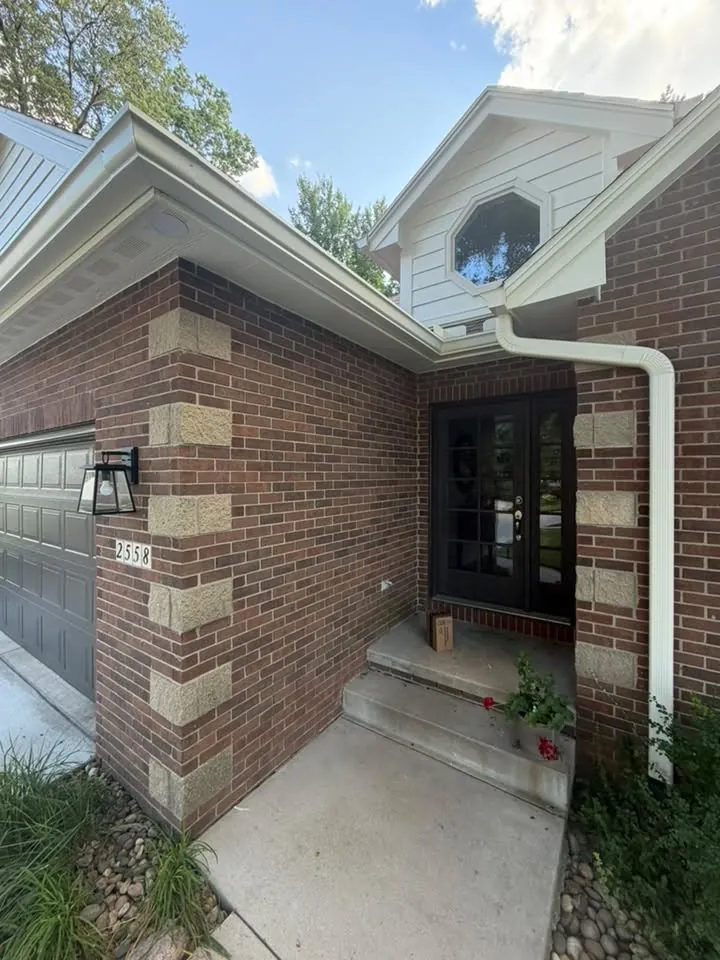Brick front entry with a white downspout beside the door