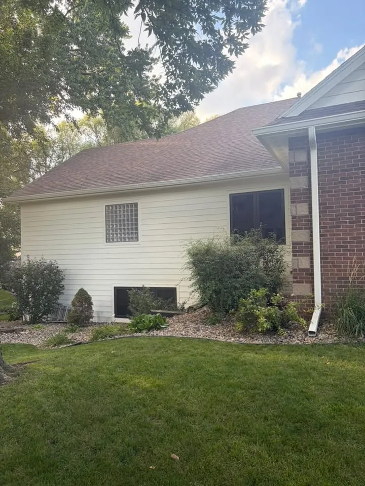 Brick and siding ranch with white gutters behind a green lawn