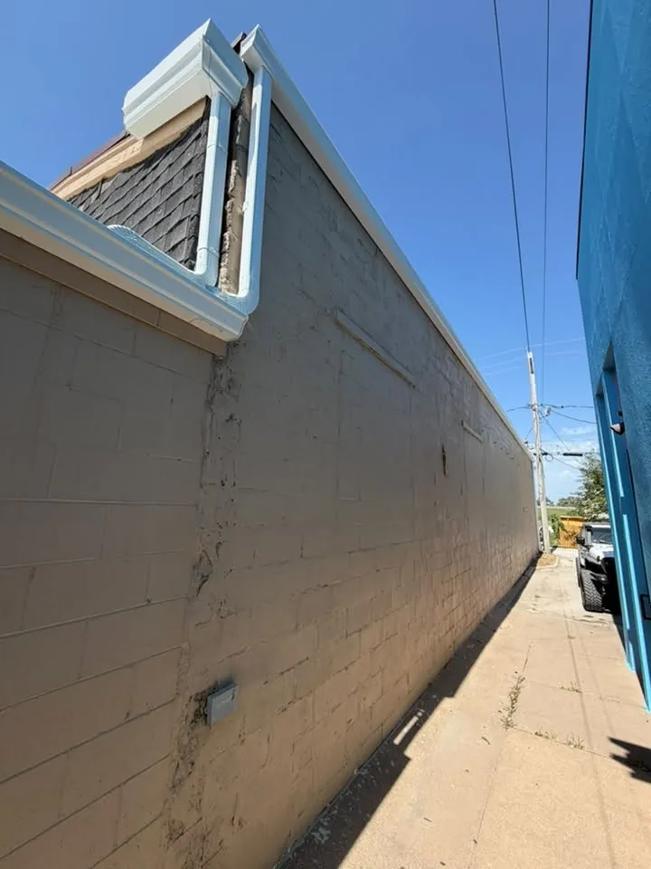 Long gutter run along the top of a tall commercial block wall