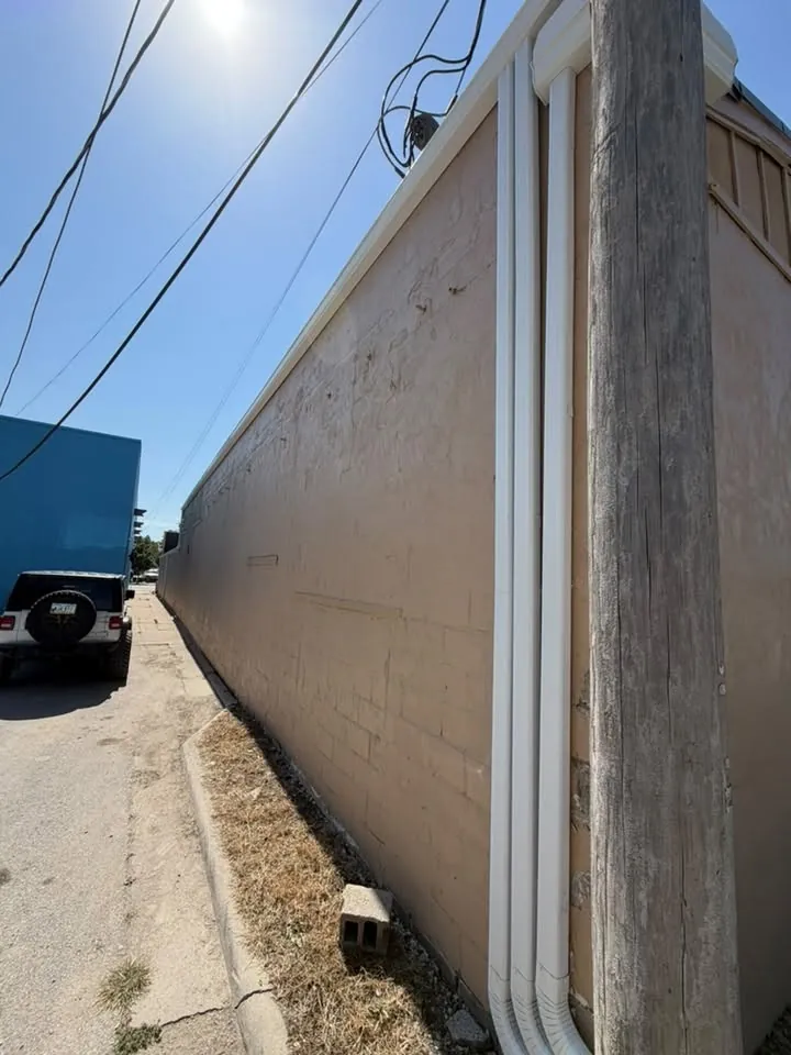 Downspout running down a tall commercial wall beside a utility pole