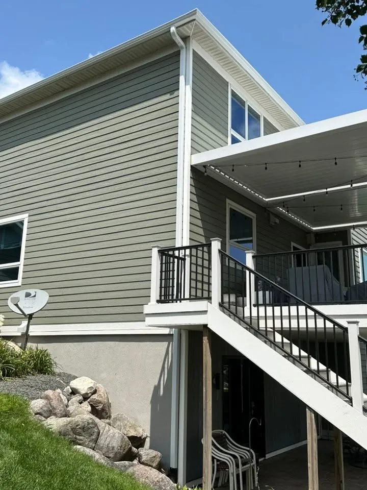 Sage green siding with white trim around a raised deck and stairs