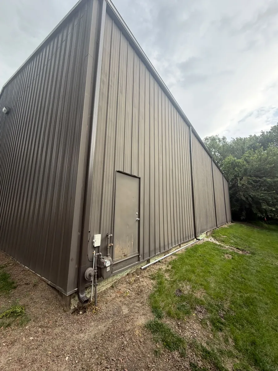 Tall brown metal building with a matching brown gutter and downspout