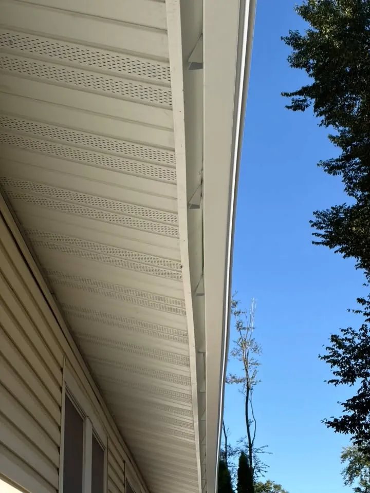 White vented soffit and fascia running along a roof edge under a blue sky