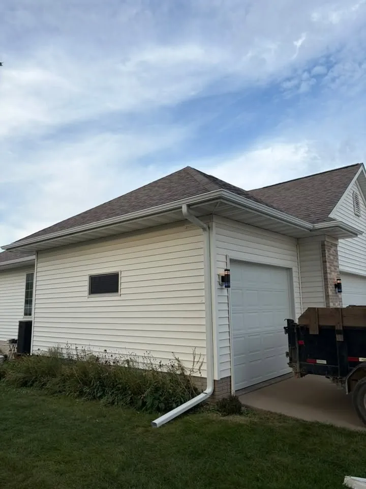 White garage with a new gutter and downspout under a blue sky