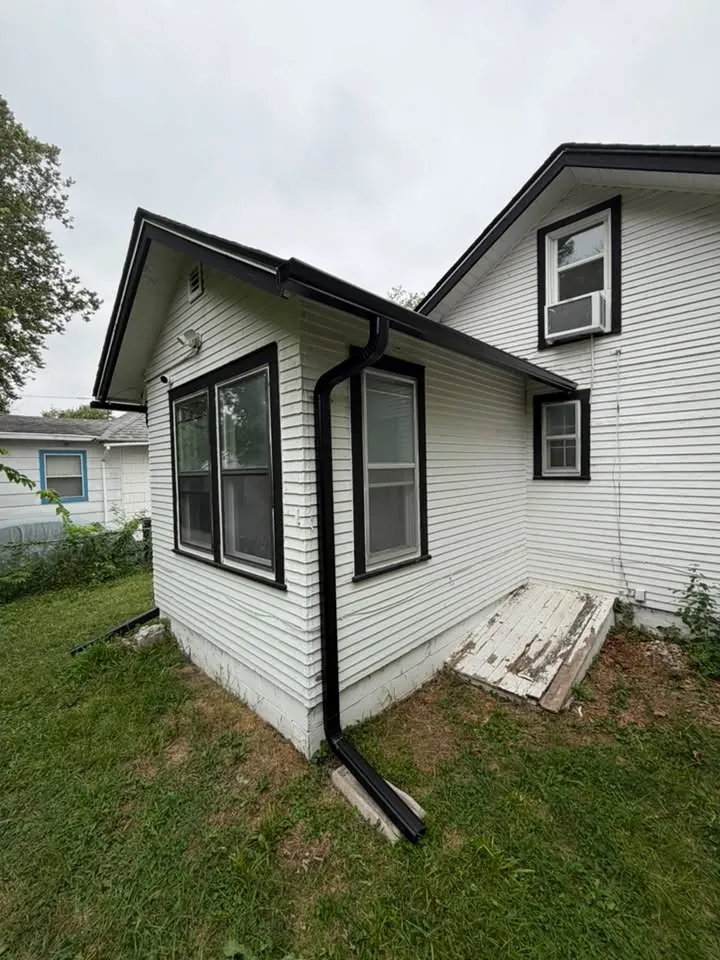 Small white home with black gutters and black framed windows