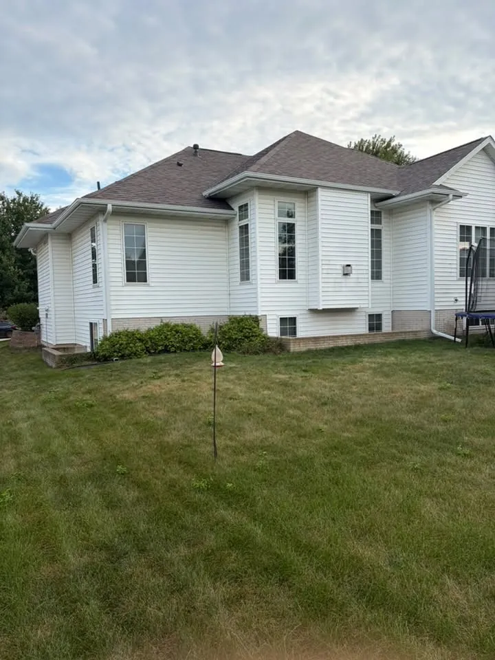 White one-story home with a hip roof and new gutters behind a mowed lawn