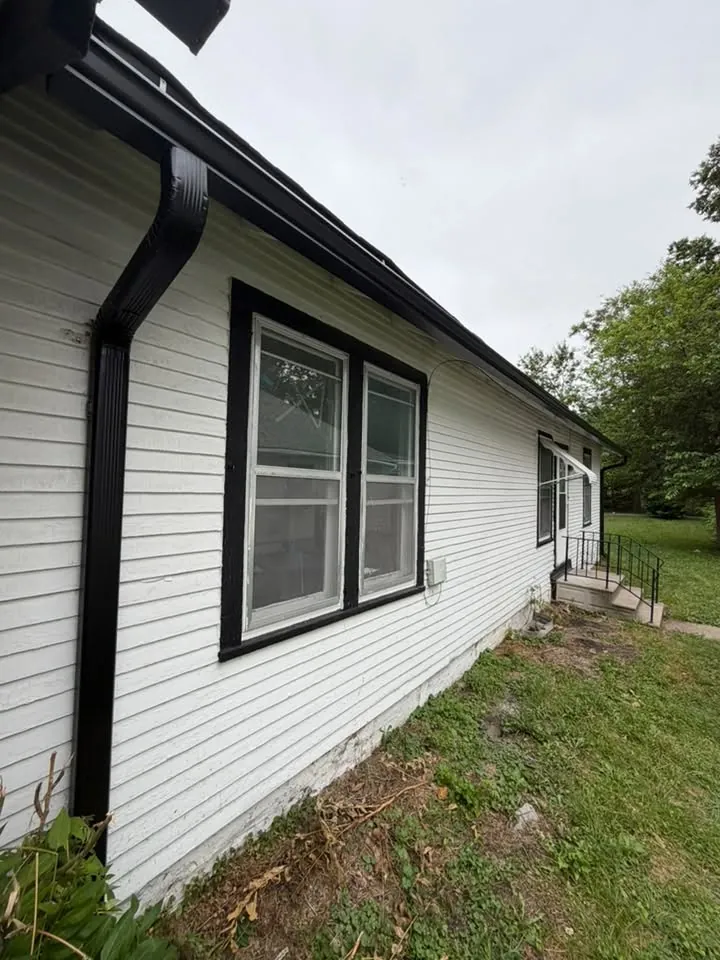 White sided home with black gutters, downspouts and black window trim
