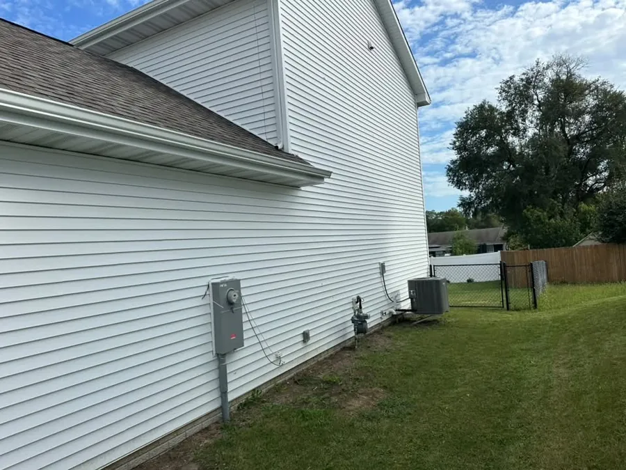Side of a home with new white siding and a gable roof
